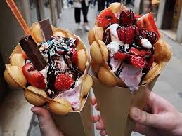 Hand holding a bubble waffle cone on a brick-paved street